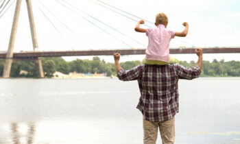 Dad and son in front of bridge showing muscles
